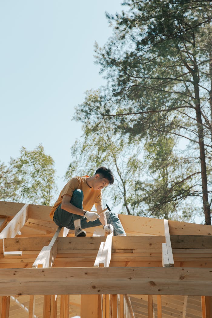 who-we-are A carpenter works on a wooden roof frame outdoors under clear skies.